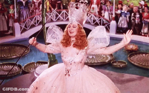 A Woman In A Fairy Costume Is Holding A Wand In Her Hand . GIF