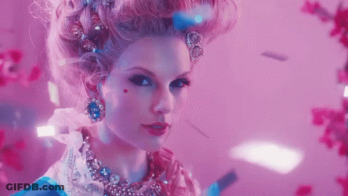 A Woman In A Fancy Dress Costume With A Heart On Her Cheek Looks At The Camera GIF