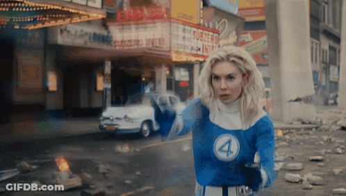 A Woman In A Fantastic Four Costume Stands In Front Of A Theatre GIF