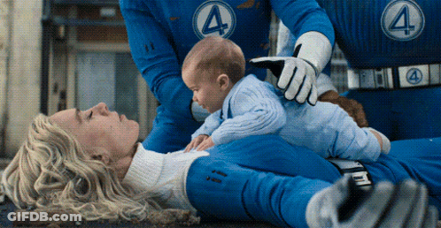 A Woman In A Fantastic Four Uniform Is Laying On The Ground With A Baby GIF