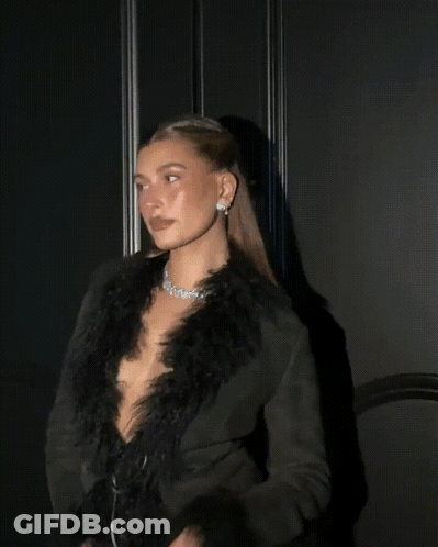 A Woman In A Feathered Coat Looks Up At The Sky GIF