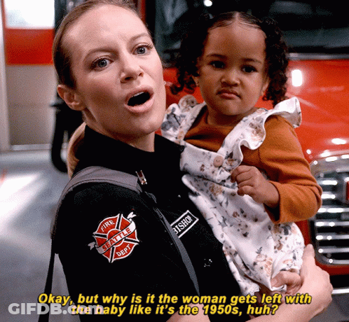 A Woman In A Fire Department Uniform Is Holding A Small Child GIF