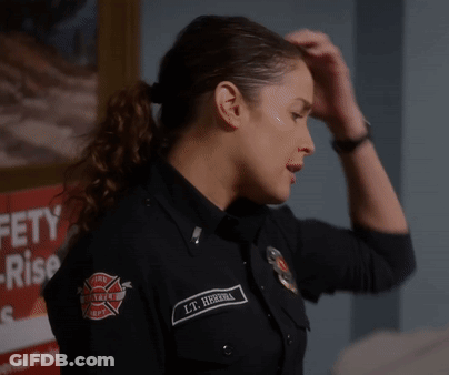 A Woman In A Firefighter Uniform Has Her Hand On Her Head In Front Of A Sign That Says Safety Rise GIF