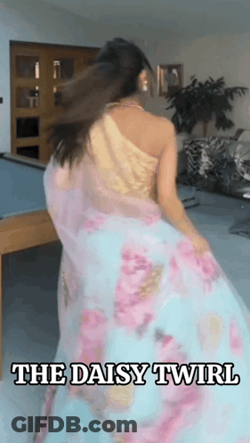 A Woman In A Floral Dress Is Dancing In A Room With The Words The Daisy Twirl Above Her GIF