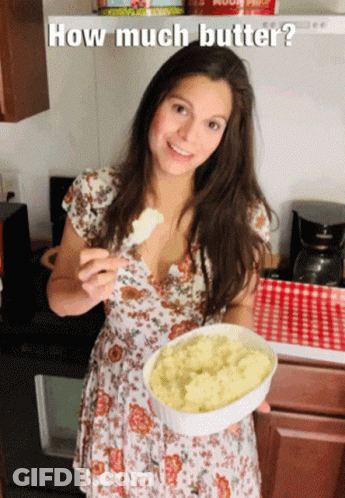 A Woman In A Floral Dress Is Holding A Bowl Of Mashed Potatoes With The Caption How Much Butter GIF