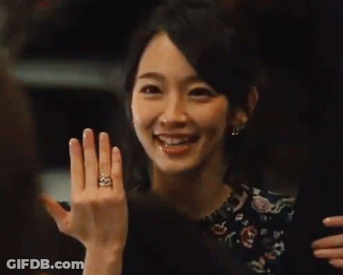 A Woman In A Floral Dress Is Laughing With Her Mouth Open . GIF