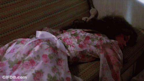 A Woman In A Floral Dress Is Laying On A Couch GIF