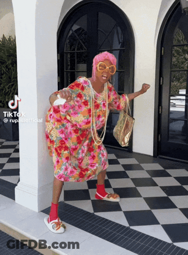 A Woman In A Floral Dress Is Standing In Front Of A Checkered Floor With Tiktok Written On The Bottom GIF