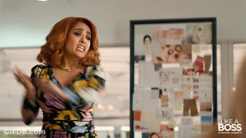 A Woman In A Floral Dress Is Standing In Front Of A Framed Picture That Says Like A Boss GIF