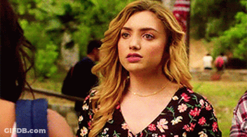 A Woman In A Floral Dress Is Standing Next To A Man In A Plaid Shirt In A Park . GIF