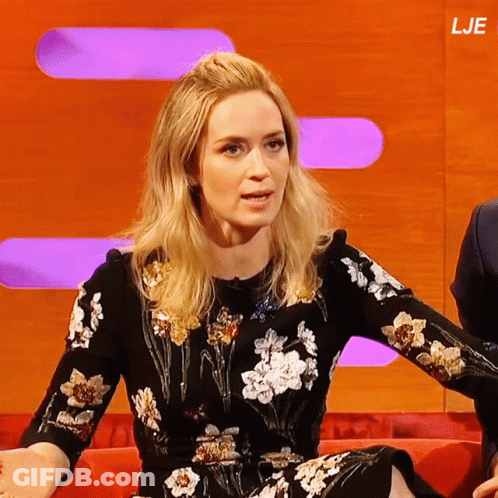 A Woman In A Floral Dress Sits On A Red Couch In Front Of A Screen That Says Lje GIF