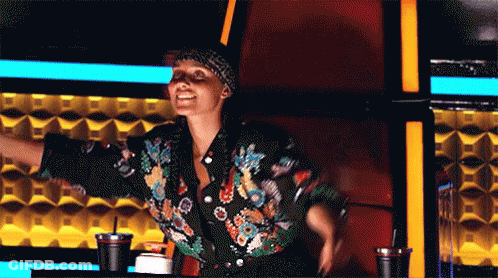 A Woman In A Floral Jacket Is Sitting In A Chair With Her Arms Outstretched .. GIF