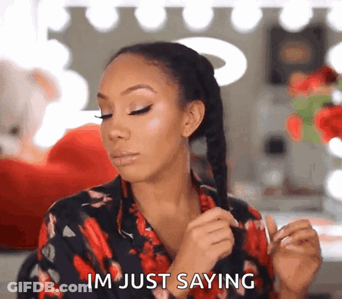 A Woman In A Floral Shirt Is Holding Her Hair And Saying Im Just Saying GIF