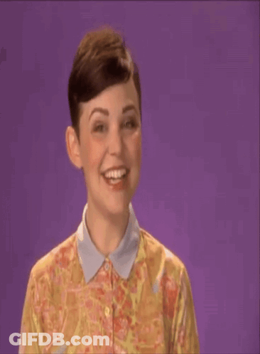 A Woman In A Floral Shirt Says Shana Tova On A Purple Background GIF