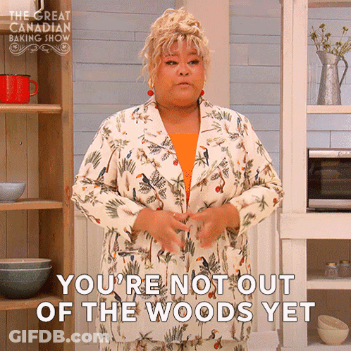 A Woman In A Floral Suit Is Standing In A Kitchen And Says You 'Re Not Out Of The Woods Yet GIF