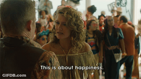 A Woman In A Fringed Top Talks To A Man In A Crowd And Says " This Is About Happiness " GIF
