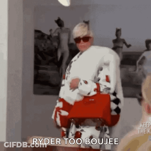 A Woman In A Fur Coat And Sunglasses Is Holding A Red Purse And Says `` Ryder Too Boujee '' . GIF