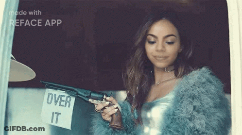 A Woman In A Fur Coat Is Holding A Gun And A Sign That Says `` Over It '' . GIF