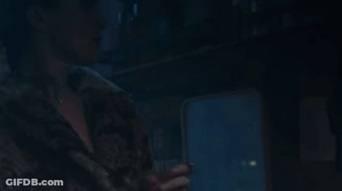 A Woman In A Fur Coat Is Looking Up At Something GIF