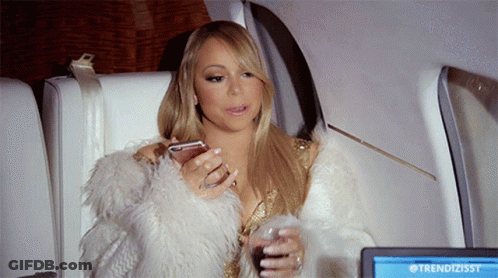 A Woman In A Fur Coat Is Sitting In Front Of A Screen That Says Trendizisst On It GIF