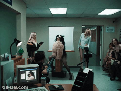 A Woman In A Fur Coat Is Standing In Front Of A Computer Screen GIF