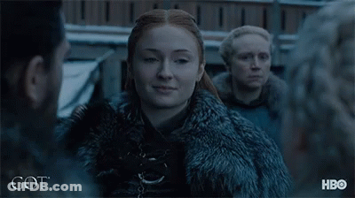 A Woman In A Fur Coat Is Standing In Front Of A Group Of People And The Word Got Is On The Bottom GIF