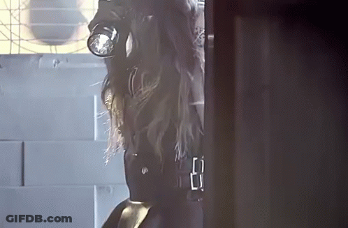 A Woman In A Gas Mask Is Standing In A Doorway GIF