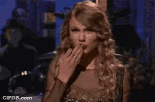 A Woman In A Gold Dress Is Blowing A Kiss . GIF