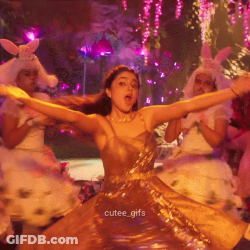 A Woman In A Gold Dress Is Dancing With Her Arms Outstretched And The Caption Cutee_gifs Is Below Her GIF