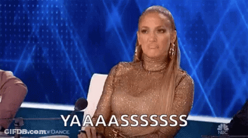 A Woman In A Gold Dress Is Sitting In Front Of A Microphone On A Stage And Making A Funny Face . GIF