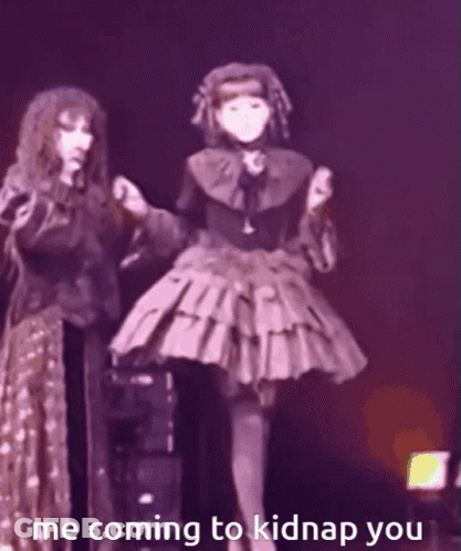 A Woman In A Gothic Dress Is Standing Next To Another Woman In A Purple Dress . GIF