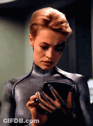 A Woman In A Gray Bodysuit Is Holding A Pen GIF