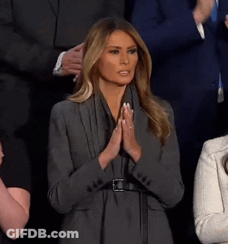 A Woman In A Gray Jacket Is Praying With Her Hands Together GIF