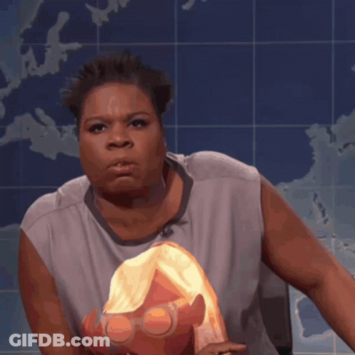 A Woman In A Gray Shirt Holds A Doll In Front Of A Map GIF