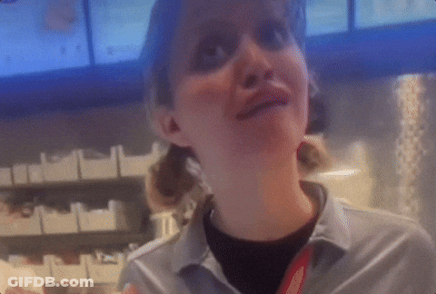 A Woman In A Gray Shirt With A Red Lanyard Around Her Neck Smiles GIF