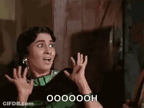 A Woman In A Green And Black Dress Is Making A Surprised Face And Holding Her Hands Up . GIF