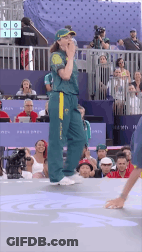 A Woman In A Green And Yellow Australia Jersey Stands In Front Of A Crowd GIF