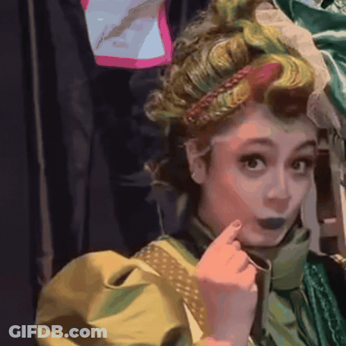 A Woman In A Green And Yellow Costume Has A Braided Headband On Her Head GIF