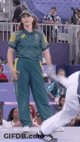A Woman In A Green And Yellow Uniform Is Standing Next To A Man In A White Uniform . GIF