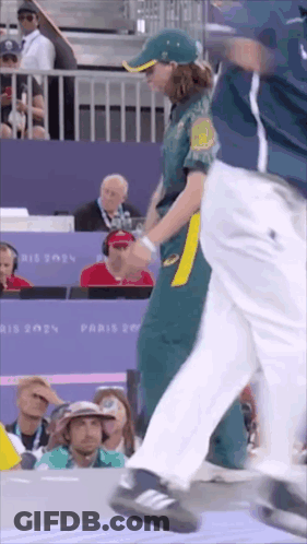A Woman In A Green And Yellow Uniform Is Walking In Front Of A Crowd At A Sports Event . GIF