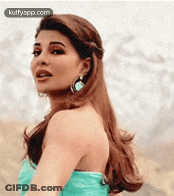 A Woman In A Green Dress And Earrings Is Looking Over Her Shoulder . GIF