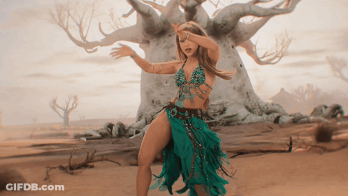 A Woman In A Green Dress Dancing In Front Of A Tree GIF