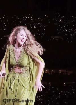 A Woman In A Green Dress Dancing On A Stage GIF