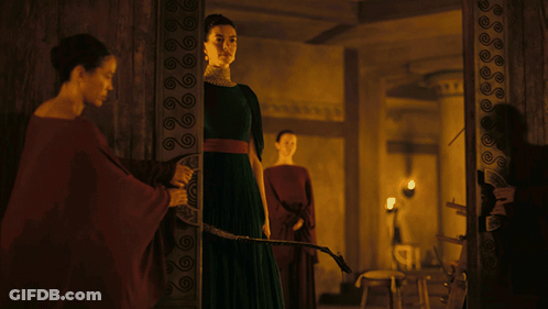 A Woman In A Green Dress Holds A Sword In A Dark Room GIF