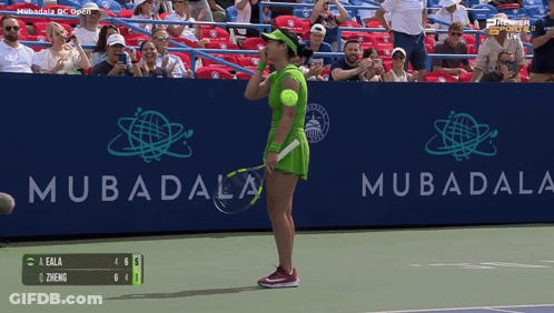 A Woman In A Green Dress Holds A Tennis Racquet In Front Of A Mubadala Sign GIF