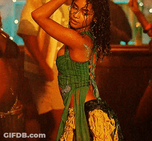 A Woman In A Green Dress Is Dancing At A Party GIF