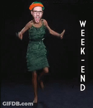 A Woman In A Green Dress Is Dancing In Front Of A Sign That Says Week End GIF