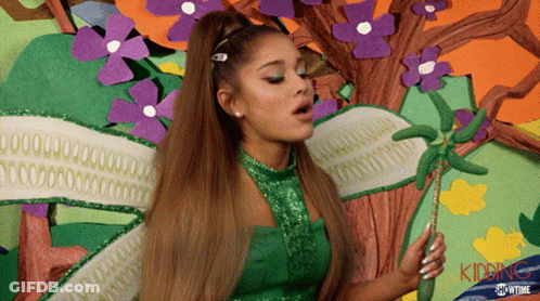 A Woman In A Green Dress Is Holding A Wand And The Word Kidding Is On The Bottom Right GIF