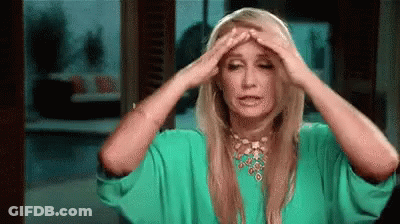 A Woman In A Green Dress Is Holding Her Head In Pain . GIF