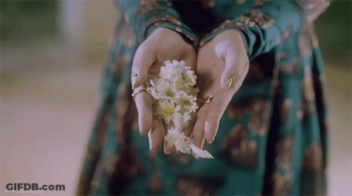 A Woman In A Green Dress Is Holding White Flowers GIF